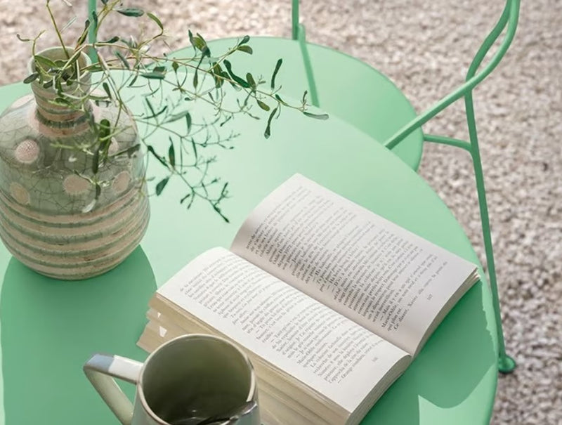 Load image into Gallery viewer, Fermob Airloop Table with 60cm diameter, modern garden table design, set in an outdoor cafe or restaurant setting.