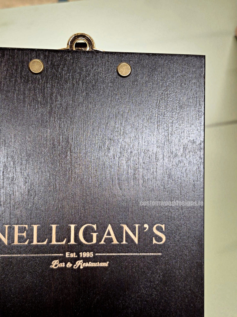 Load image into Gallery viewer, Set of 24 branded A5 wooden clipboards with Custom Wood Designs logo, displayed on hospitality and hotel menu setup.