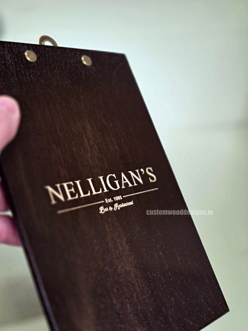 Load image into Gallery viewer, Set of 24 branded A5 wooden clipboards from Custom Wood Designs displayed on a hospitality counter, ideal for menus and notes.