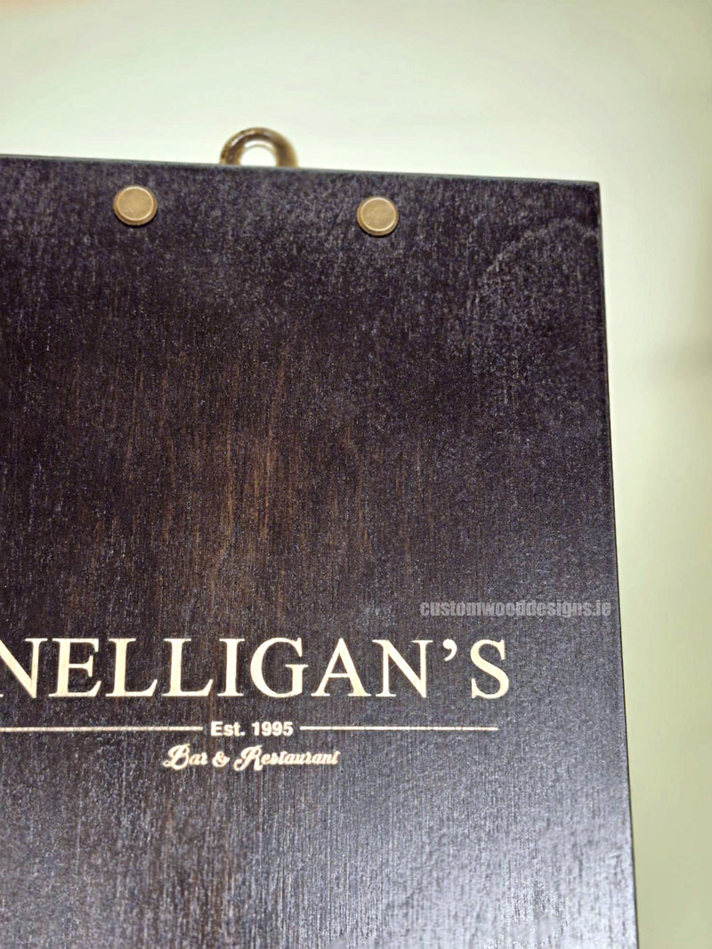 Load image into Gallery viewer, Set of 24 premium wooden A5 clipboards with Custom Wood Designs branding, displayed on a hospitality or café counter.