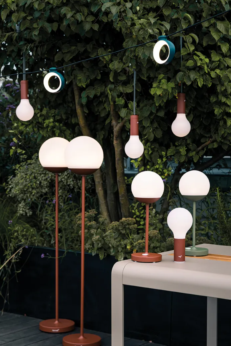 Fermob HOOPIK outdoor string lights hanging over a restaurant patio, providing warm ambient lighting for outdoor dining.