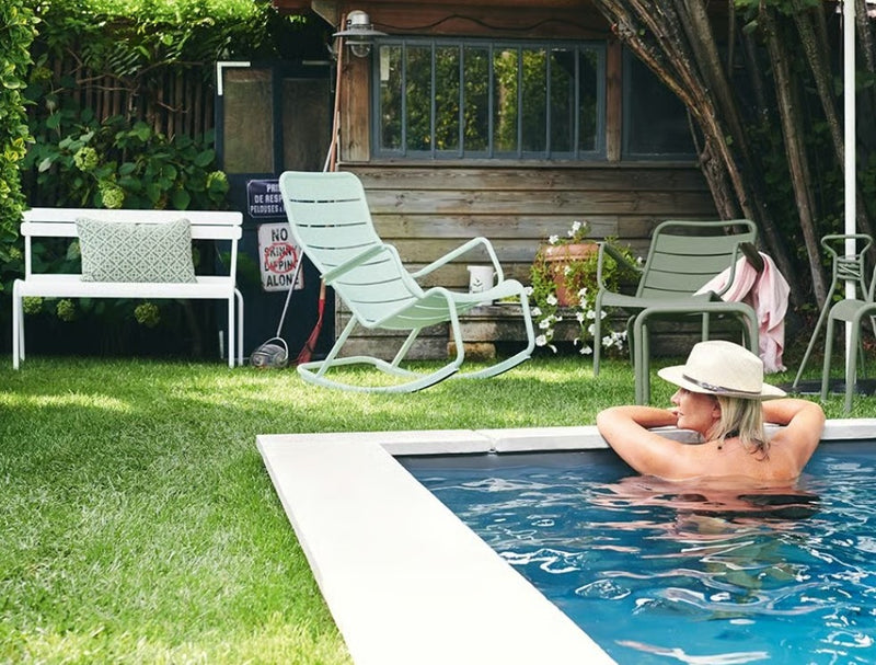 Load image into Gallery viewer, Green Fermob Luxembourg outdoor rocking chair with metal frame and slatted seat, perfect for patio relaxation.