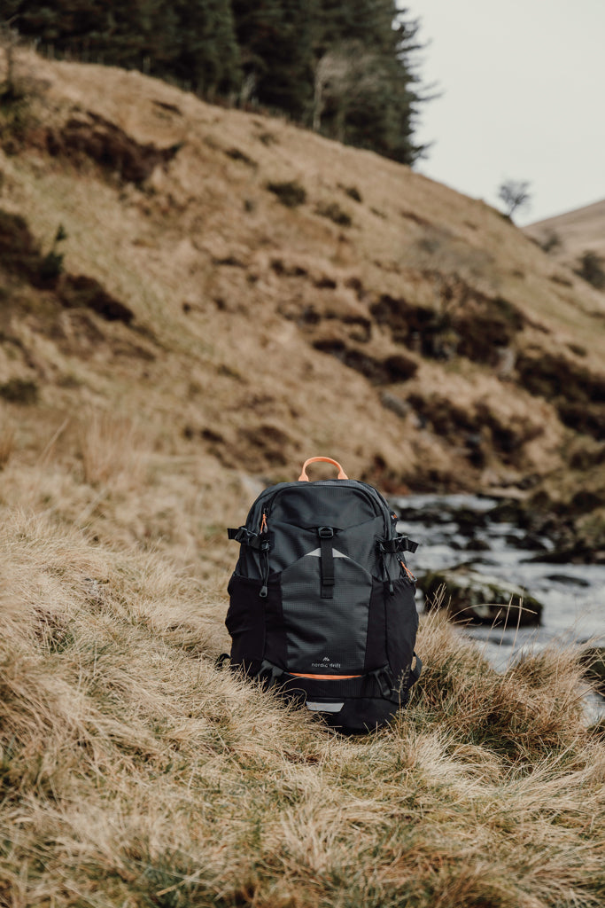 Load image into Gallery viewer, Nordic Drift Trail RCS 24L backpack showing durable black fabric, multiple compartments, and adjustable straps for outdoor travel.