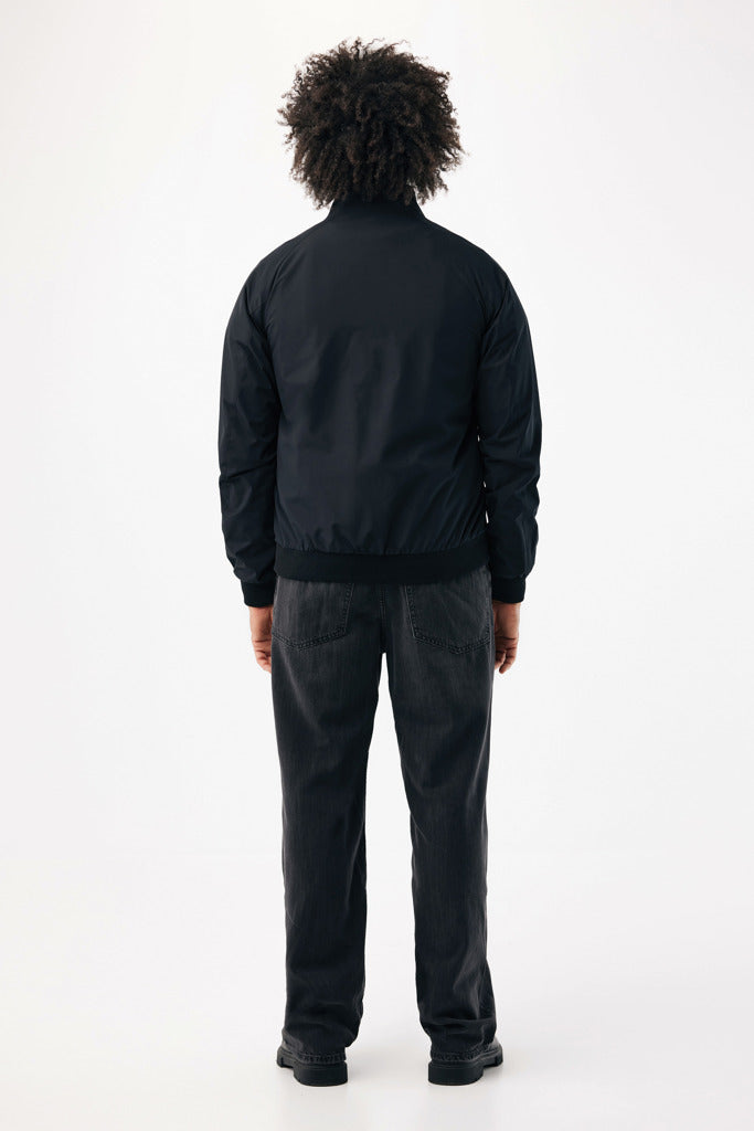 Load image into Gallery viewer, Iqoniq Odin recycled polyester urban jacket textile in black, showing the jacket's front view with hood and zipper closure.