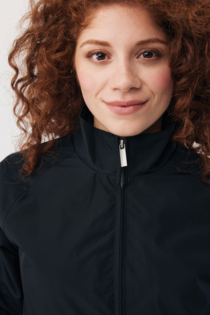 Load image into Gallery viewer, iqoniq Odin recycled polyester urban jacket, close-up view showing black textile fabric and sleek design details.