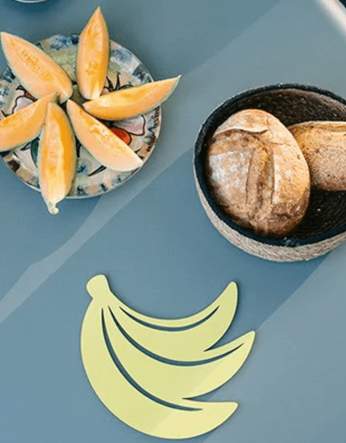 Load image into Gallery viewer, Fermob banana-shaped metal trivet and non-slip heat pad, 23x24.4 cm, designed to protect surfaces from hot cookware.