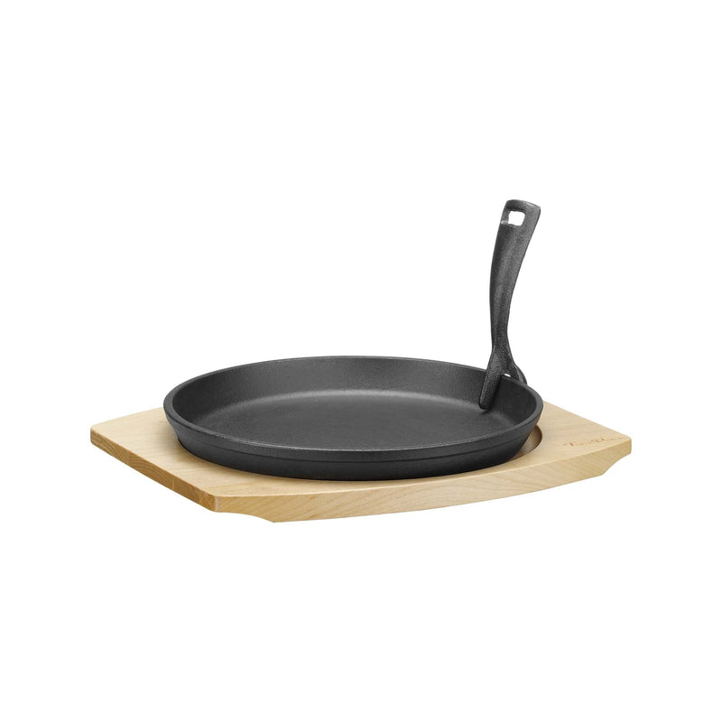 Load image into Gallery viewer, Cast iron serving pan with wooden base and handle, 220mm diameter, from Fine Dine, shown on a kitchen countertop.