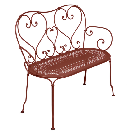 Red Fermob 1900 decorative bench with a sleek, modern design and curved metal frame for indoor or outdoor use.