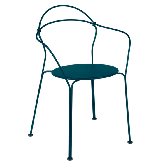 Fermob Airloop Lounge Chair with woven metal frame and curved armrests for outdoor relaxation, set on a patio.