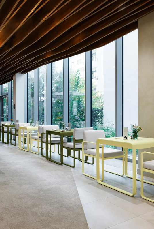 Fermob Bellevie outdoor dining armchair with a Nutmeg Grey finish, featuring a comfortable armrest and stylish design.
