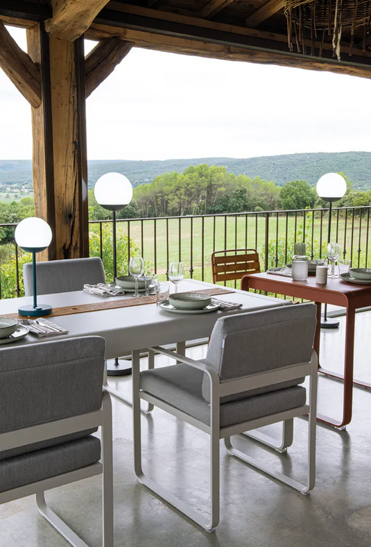 Fermob Bellevie outdoor dining armchair with a nutmeg grey toupet cushion and armrests, designed for comfortable outdoor seating.