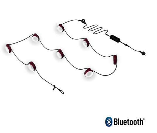 Fermob HOOPIK black cherry string lights, 1200 cm outdoor lighting for restaurant or hotel ambiance in a nighttime setting.