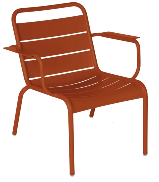 Candied orange Fermob Luxembourg garden lounge armchair with curved metal frame and plush cushion for outdoor relaxation.
