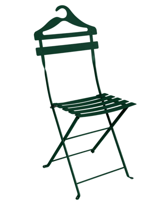 Fermob Cedar Green folding Bistro Valet Chair hanging on a metal frame, showcasing its foldable design and sturdy metal construction.