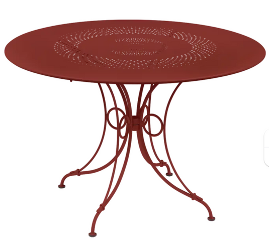 Round Fermob 1900 outdoor table with 117 cm diameter in vibrant Chilli color, ideal for garden or patio use.