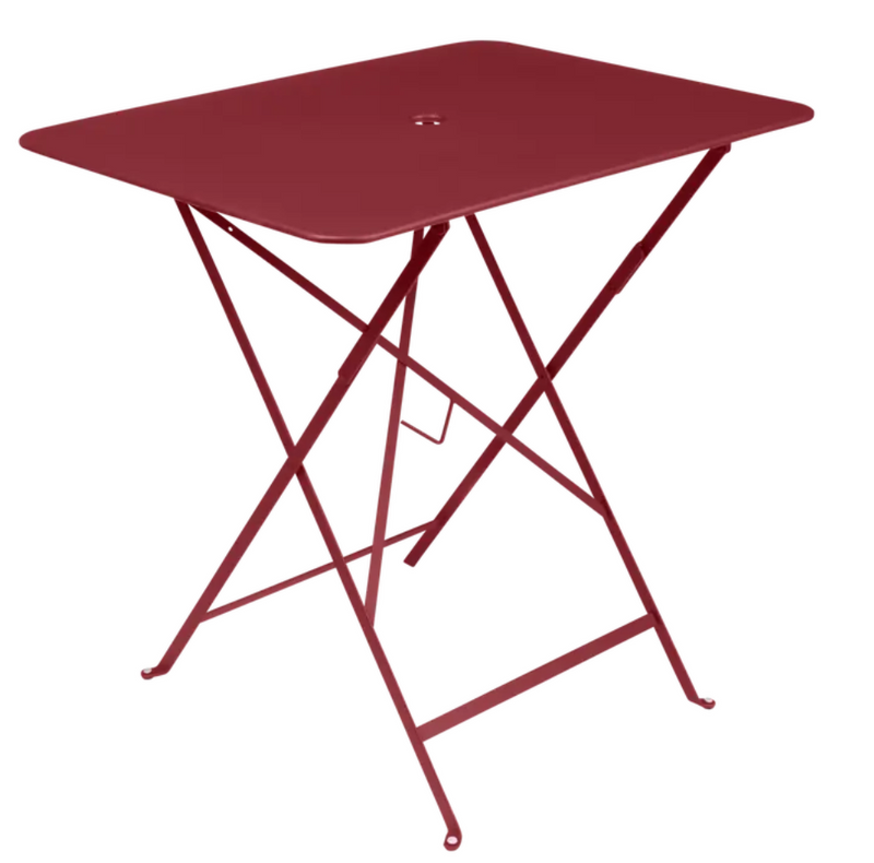 Load image into Gallery viewer, Fermob foldable bistro table 77x57 cm with metal frame, suitable for outdoor use, shown outdoors with a vibrant setting.
