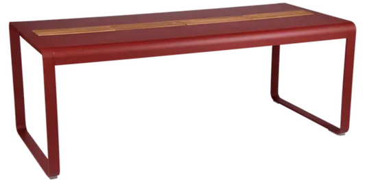 Fermob Bellevie outdoor dining table in wood and metal, 196x90 cm with storage, eight-seater, shown in a vibrant chili color.