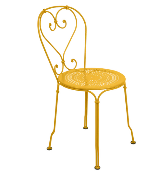 Fermob Honey 1900 outdoor chair with curved backrest and armrests, made of durable metal in a honey yellow finish.
