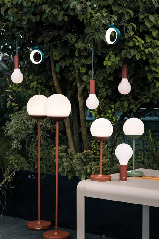 Fermob HOOPIK outdoor string lights hanging over a restaurant patio, providing warm ambient lighting for outdoor dining.