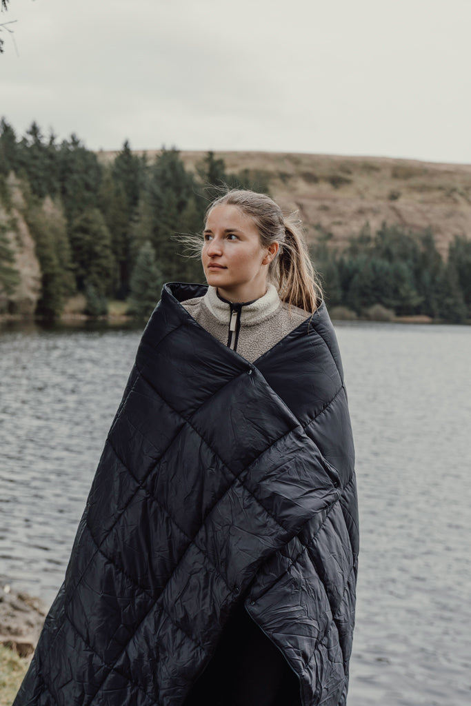 Load image into Gallery viewer, Nordic Drift GRS 3-in-1 adventure outdoor blanket spread on grassy terrain, versatile and warm for camping and outdoor activities.
