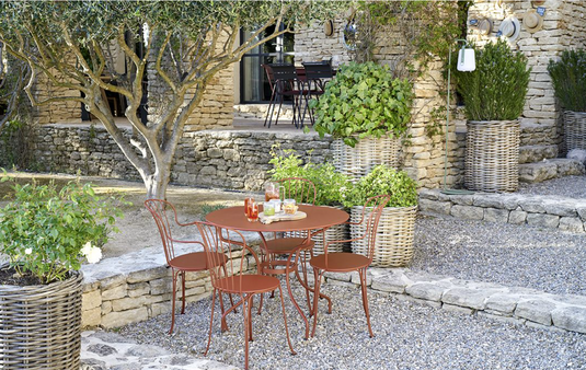 Fermob OPÉRA+ outdoor metal table with 96 cm diameter in red ochre, designed for patio dining and outdoor gatherings.