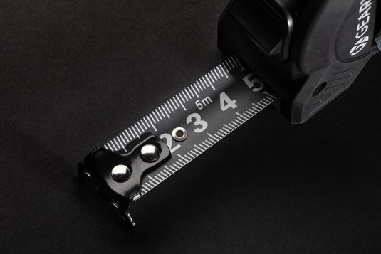 Gear X 5M measuring tape with slow/fast retract function, durable tools and torches, close-up of tape retraction mechanism.