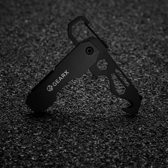 GearX foldable EDC tool with carabiner and parcel cutter, compact multi-tool for everyday carry, black finish, open with multiple functions visible.