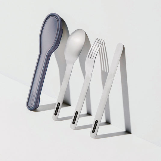 Black+Blum outdoor cutlery set with stainless steel forks, knives, and spoons arranged on a wooden surface.
