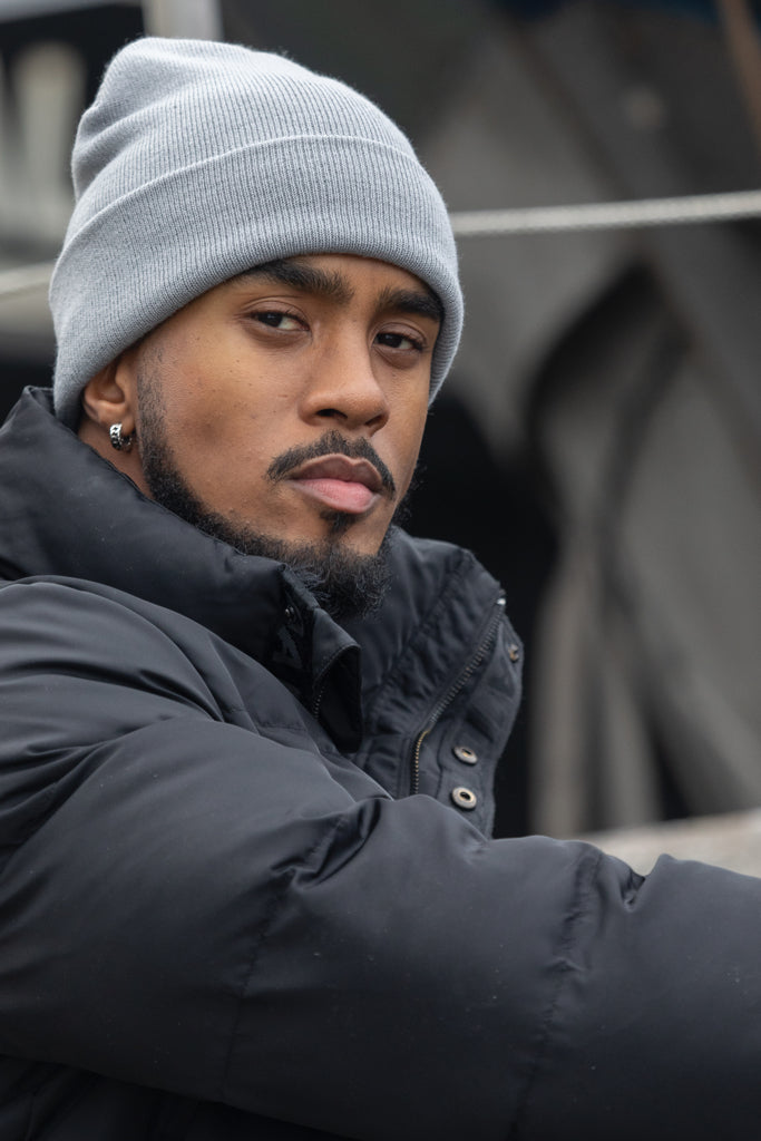 Load image into Gallery viewer, Polylana® beanie headwear by XD Collection featuring a cozy, knitted design in neutral tones, perfect for cold weather.
