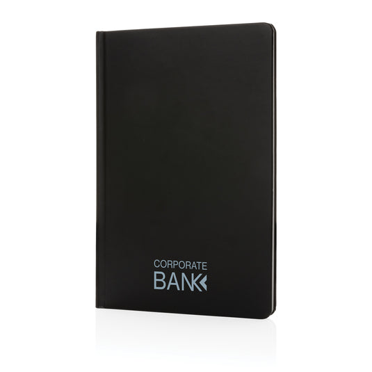 A5 Impact Stone Paper Hardcover Notebook by XD Collection, featuring a durable black cover and spiral binding on a wooden surface.