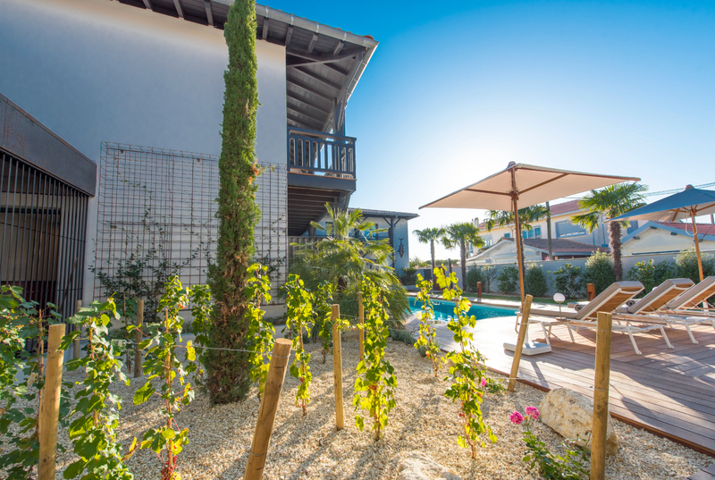 Load image into Gallery viewer, Fermob Pilotis teak sunlounger with a sleek design, ideal for poolside relaxation in hotel or outdoor settings.
