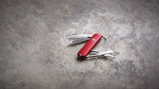 Victorinox Classic SD pocket knife with 7 tools, including blade, scissors, and nail file, displayed open on a white background.
