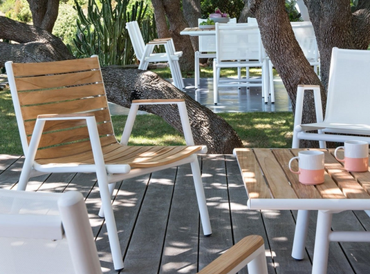 Red ochre Fermob Pilotis teak outdoor armchair with low arms, showcasing solid teak construction and modern design.