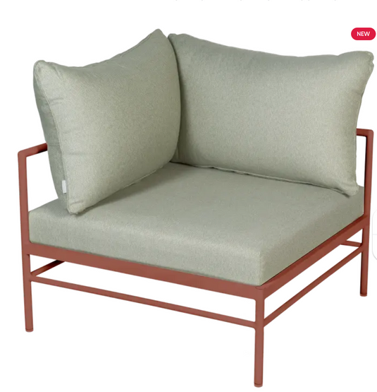 Red and meadow green Fermob Rivage corner outdoor armchair with metal frame, designed for comfortable outdoor lounging.