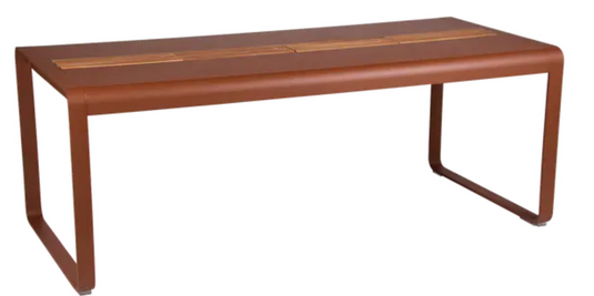 Red Fermob Bellevie outdoor dining table with wood and metal construction, 196 x 90 cm, eight-seater with built-in storage.
