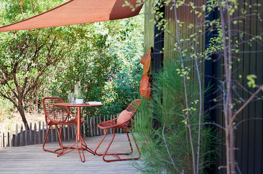 Red woven Fermob Sixties Low Armchair, stylish outdoor lounge chair with low arms, perfect for outdoor restaurant seating.