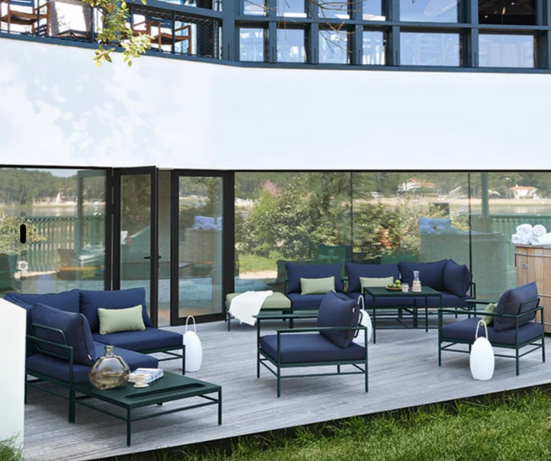 Load image into Gallery viewer, Fermob Rivage Ottoman outdoor furniture with metal frame, shown with protective cover on a patio setting.

