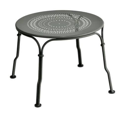 Fermob 1900 low table with a 45 cm diameter, metal surface and modern design, shown in a garden setting.