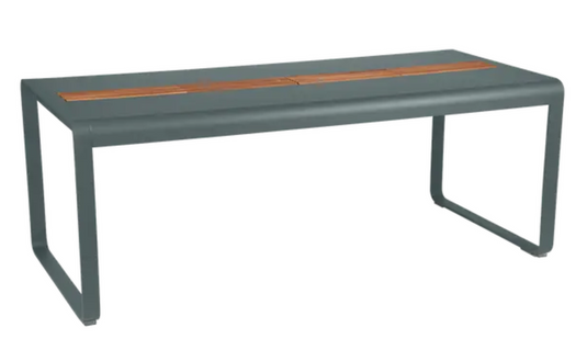 Storm grey Fermob Bellevie outdoor dining table with wood and metal design, featuring storage, seats eight comfortably.