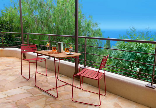 Fermob outdoor teak table measuring 90x60cm with smooth wooden surface and modern design for outdoor dining or patio use.