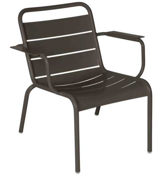 Fermob Luxembourg garden armchair lounge with a curved metal frame and cushioned seat in a cozy outdoor setting.