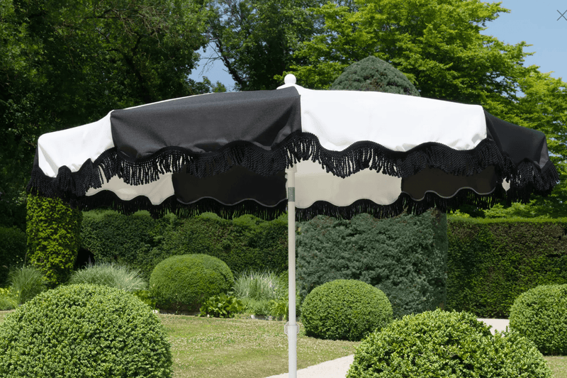 Load image into Gallery viewer, Aluminium parasol with 250cm diameter wave finish and fringe, designed by Custom Wood Designs, outdoors in a garden setting.
