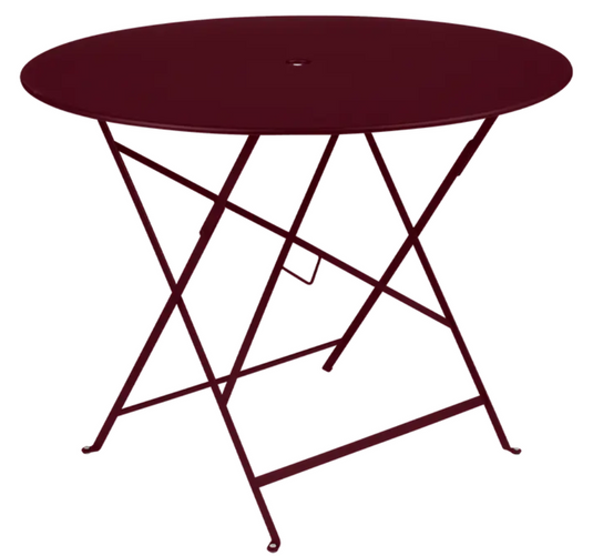 Fermob round bistro table with deep red metal finish, 96cm diameter, outdoor suitable with central parasol hole.