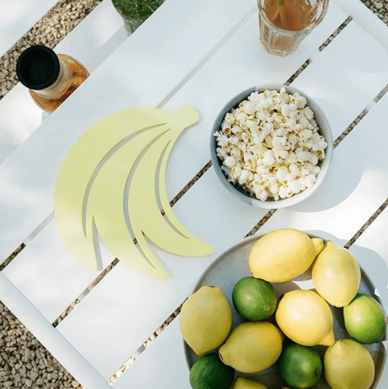 Load image into Gallery viewer, Fermob banana-shaped non-slip metal heat pad trivet measuring 23x24.4 cm, designed to protect surfaces from hot cookware.
