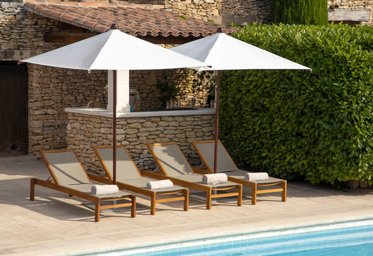 Fermob IBIZA teak sunlounger with a slatted outdoor sun bed design on a beach setting