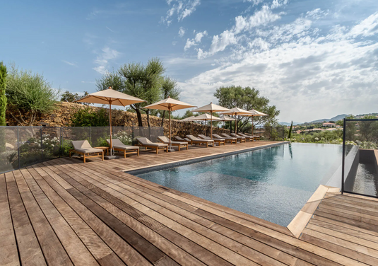 Fermob IBIZA teak sunlounger on beach, outdoor teak sunbed with adjustable backrest and modern design, ideal for relaxing outdoors.