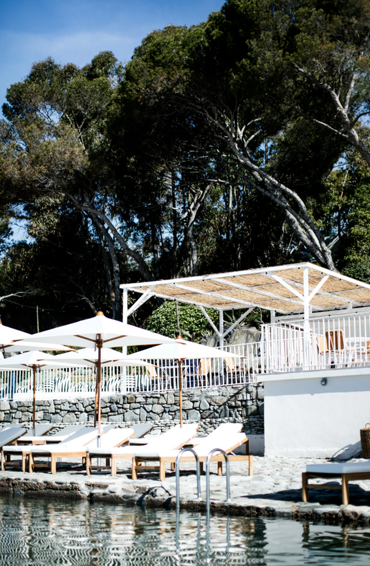 Fermob IBIZA teak sunlounger with adjustable backrest on a sandy beach, ideal for outdoor sunbathing and relaxation.