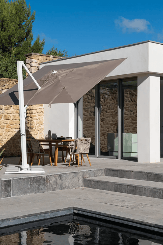 Fermob Borée 3x3m outdoor commercial parasol with base and sealing plate for hospitality spaces, shown open in a patio setting.