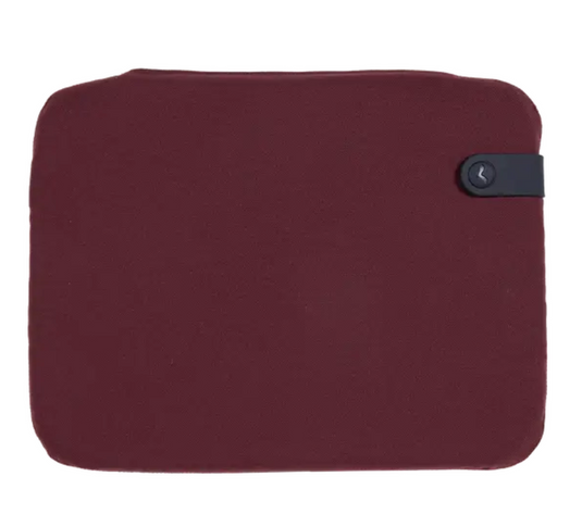 Burgundy Fermob outdoor cushion 38x30cm on chair seat, designed for outdoor use, with soft fabric and plush padding.