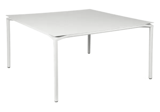 White Fermob CALVI square dining table, 140x140 cm, designed for eight seats, with a sleek metal surface.